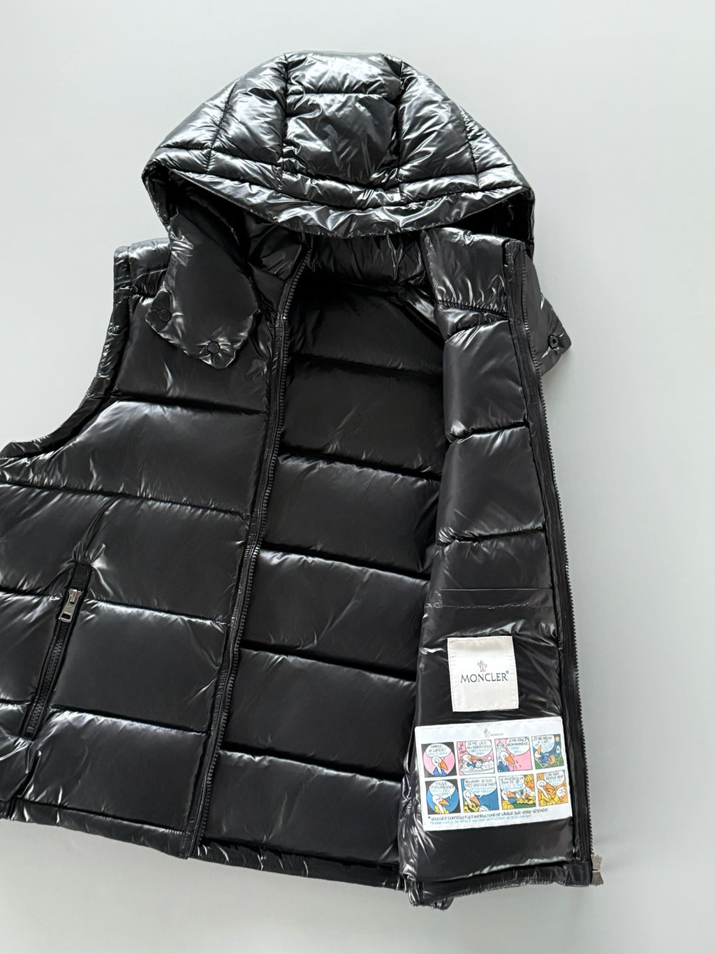 Black hooded puffer jacket with zip front; visible inner label and logo patch.