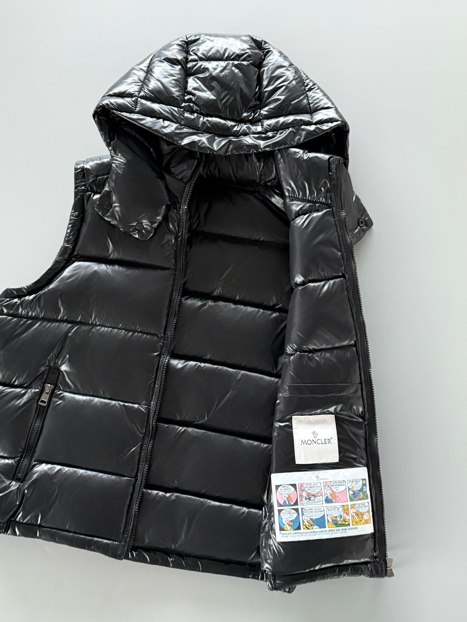 Black hooded puffer jacket with zip front; visible inner label and logo patch.