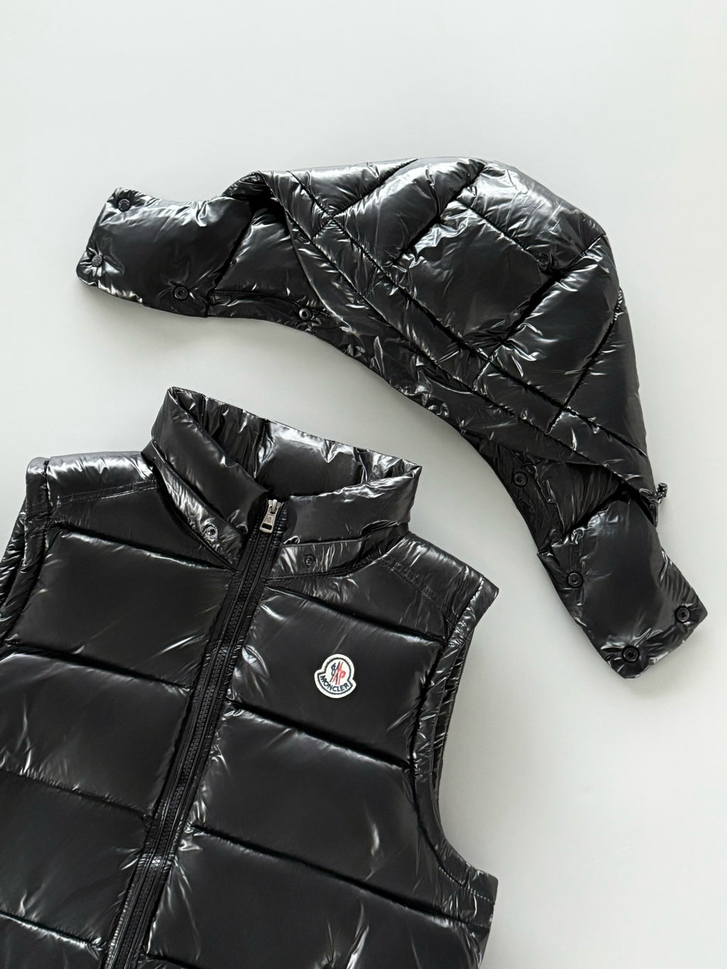 Black hooded puffer jacket with quilted panels and zip front; Moncler chest logo patch.