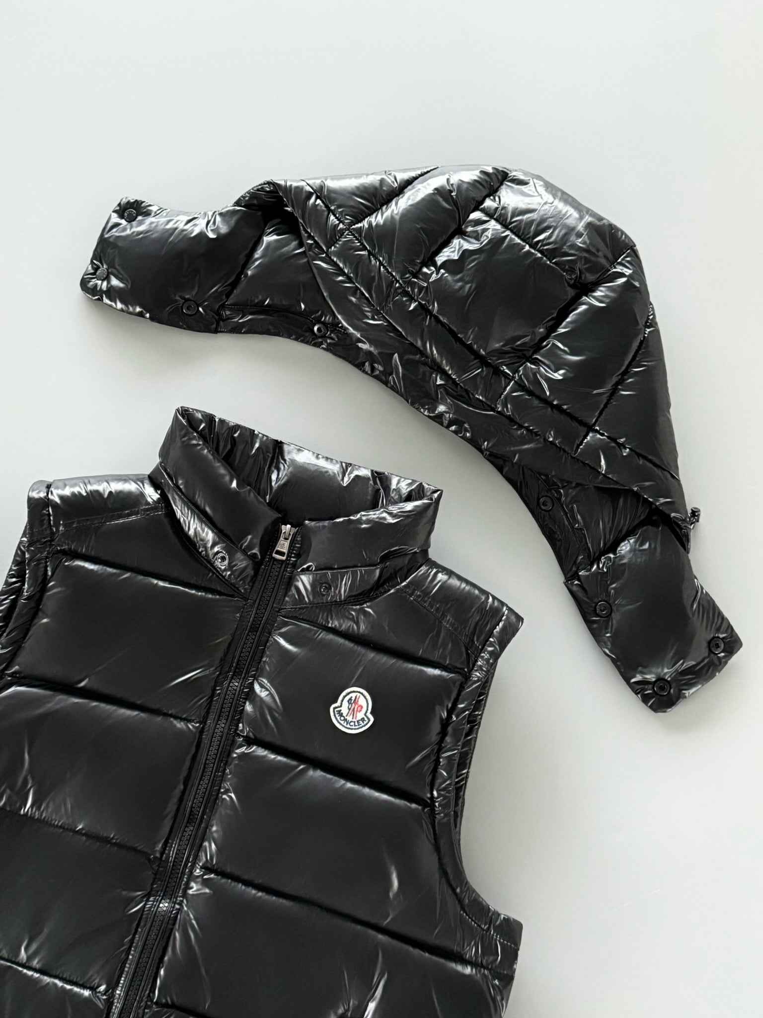 Black hooded puffer jacket with quilted panels and zip front; Moncler chest logo patch.