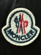 Embroidered Moncler logo patch in red and blue on black fabric.