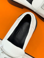 Hermes white leather loafer showing black interior lining and stamped logo