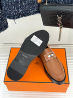 Hermes women’s tan loafer bottom view with black sole and square buckle strap
