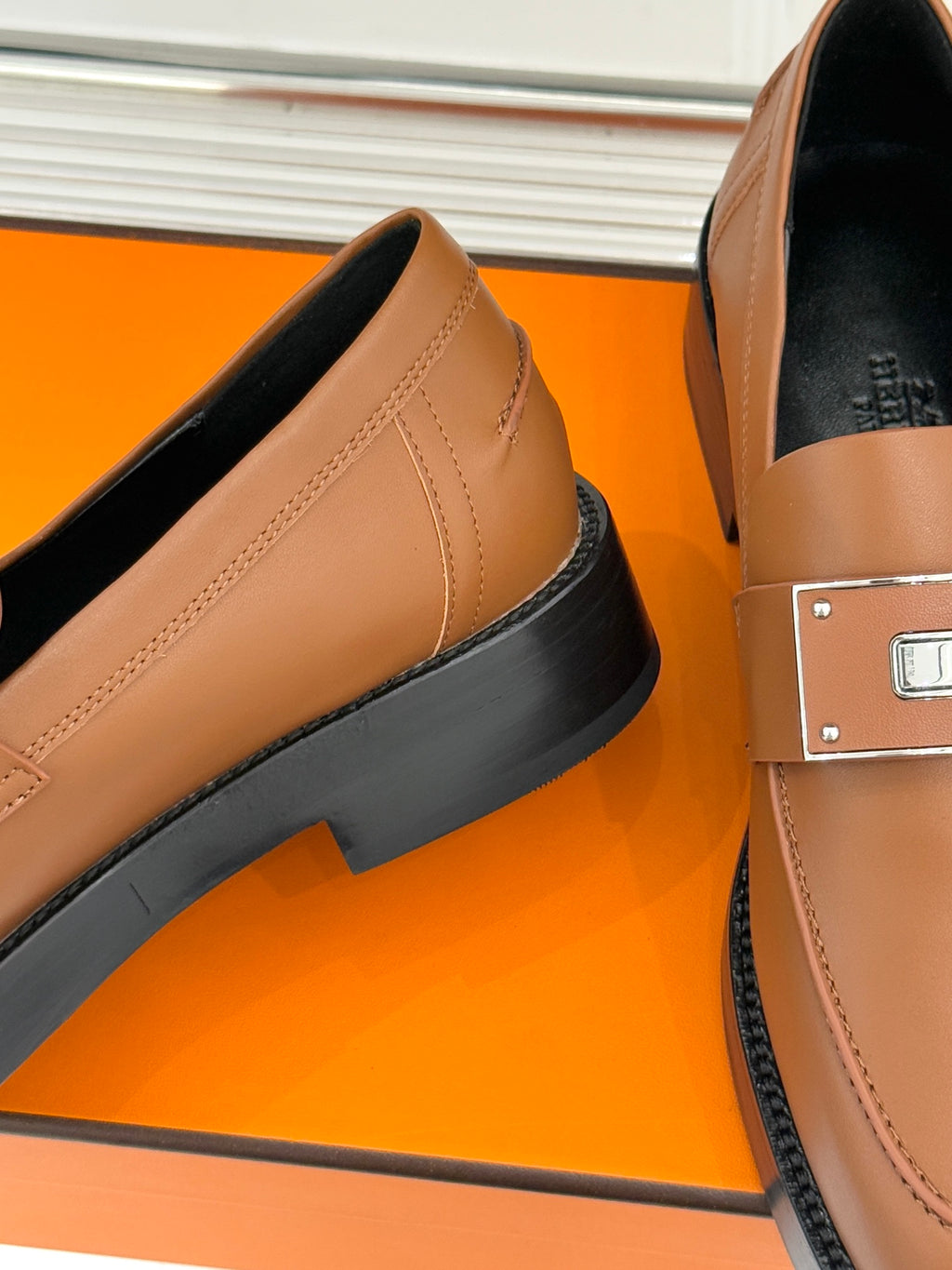 Hermes women’s tan leather loafer side view with thick dark rubber sole and stitching