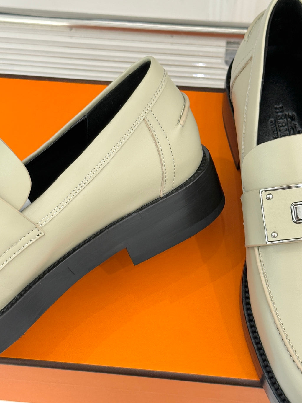 Hermes women's cream slip-on shoe close-up: black outsole edge and stitched side
