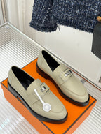 Hermes women's cream slip-on shoes on display box with black side trim and silver buckle