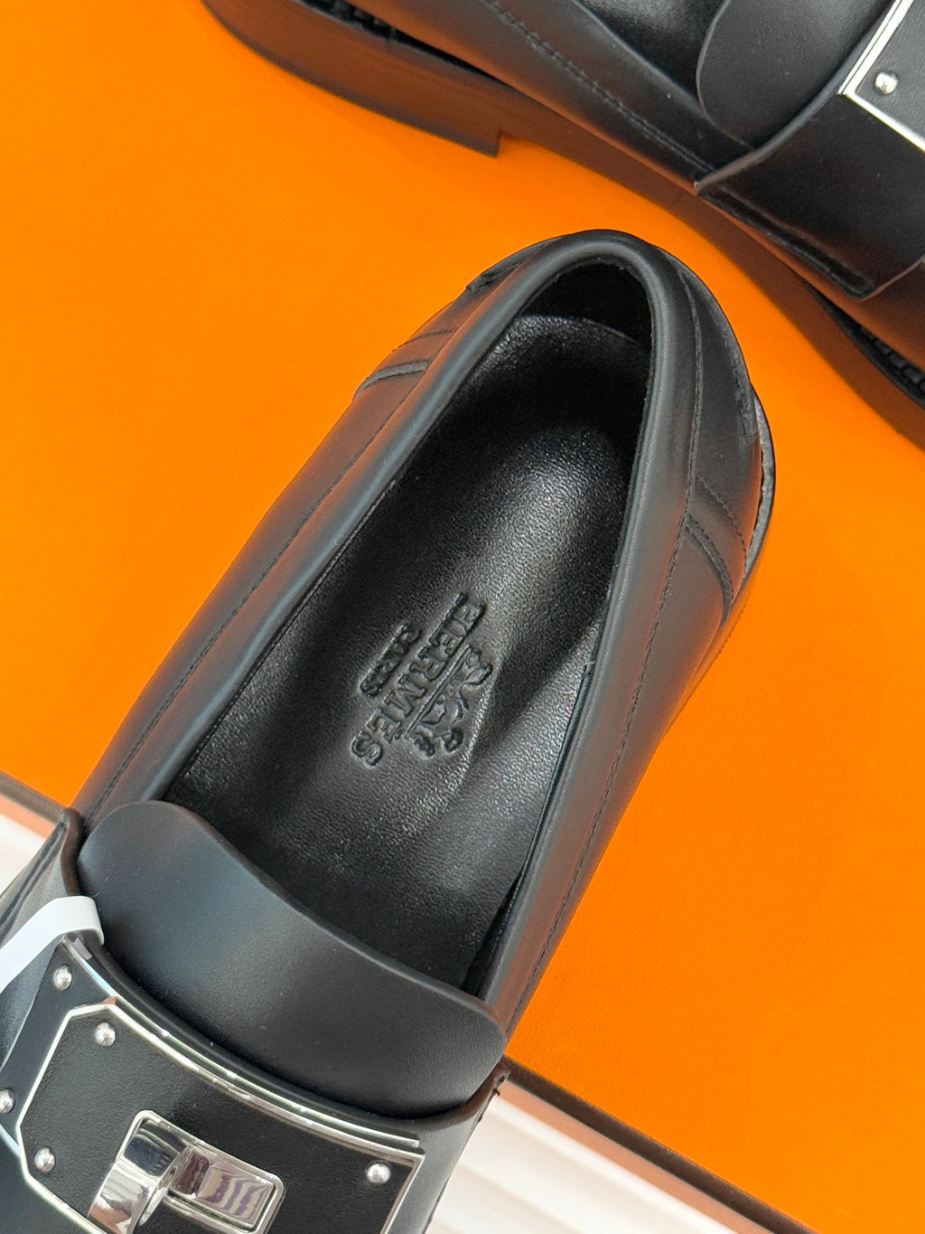 Black leather loafer insole close-up with embossed brand text