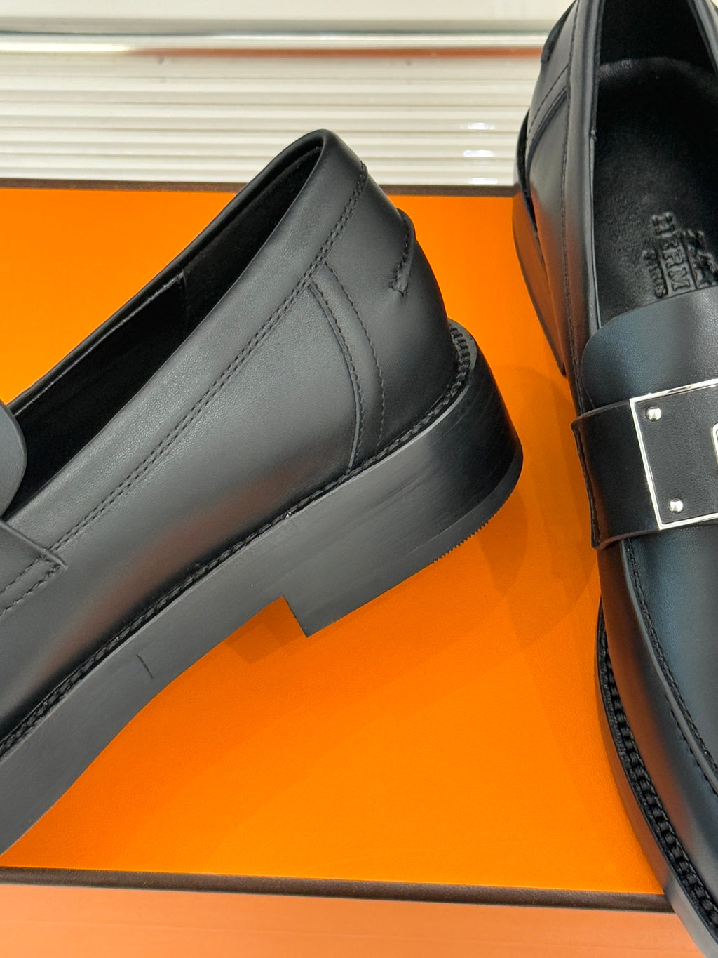Black leather loafer side view with stitched panel and block heel