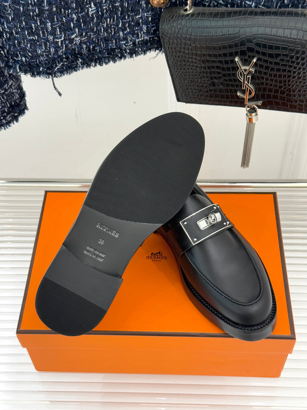Black leather loafer pair on box, showing sole profile and buckle strap