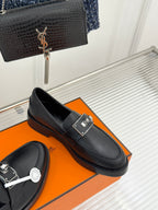 Black leather loafers with silver buckle strap and rounded apron toe