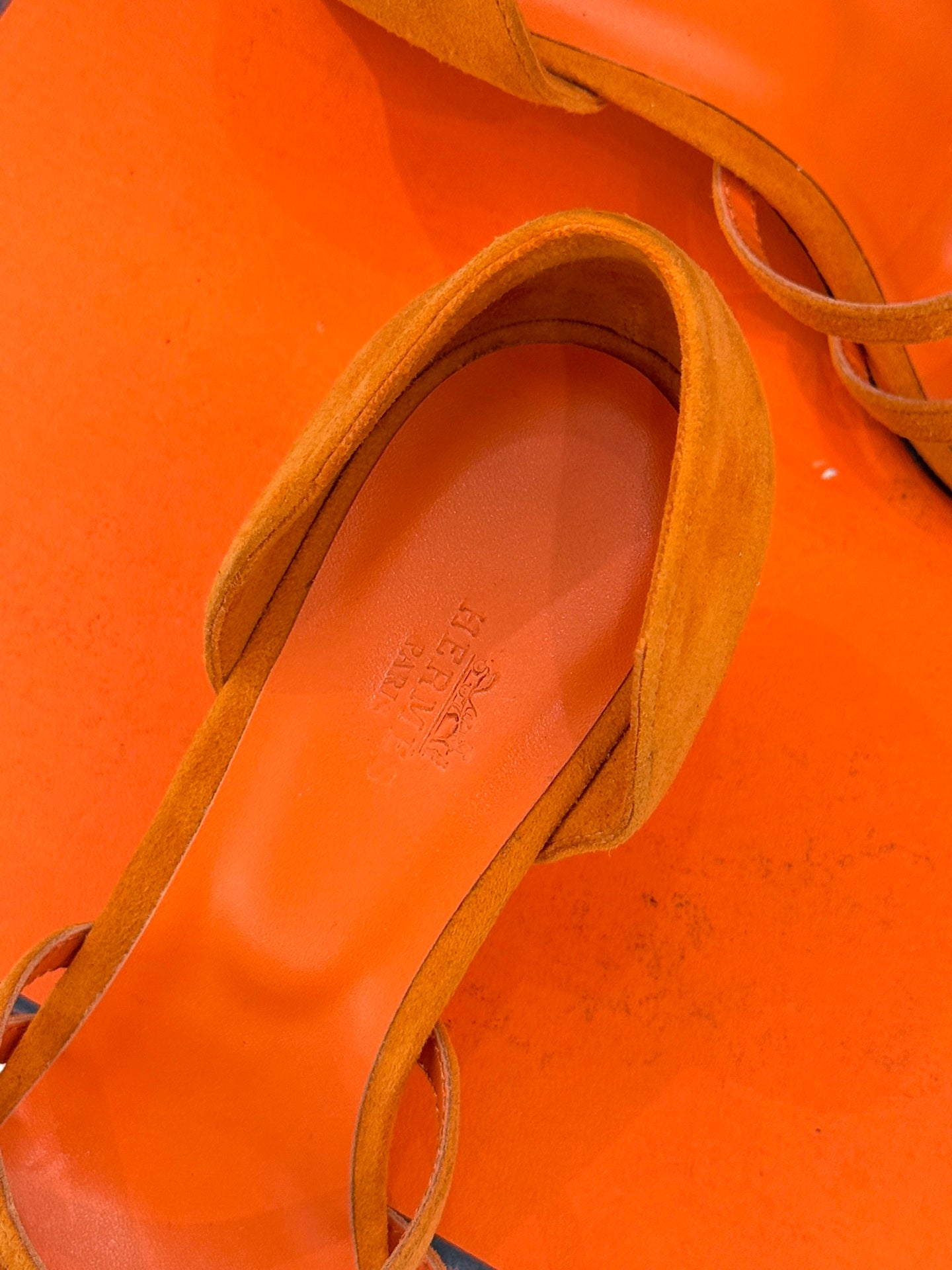 Hermes orange suede sandal close-up showing footbed and side strap