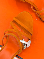 Hermes orange suede sandals close-up with strap detail and small silver hardware tag