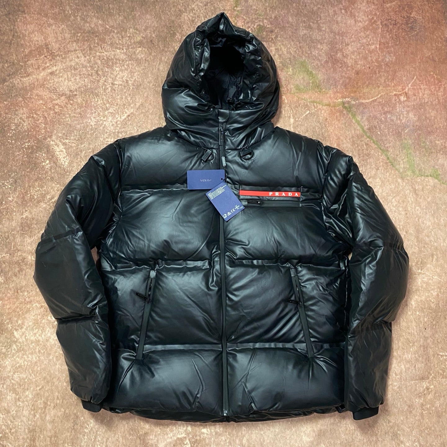 Men's long hooded puffer jacket in dark color, full zip and quilted panels