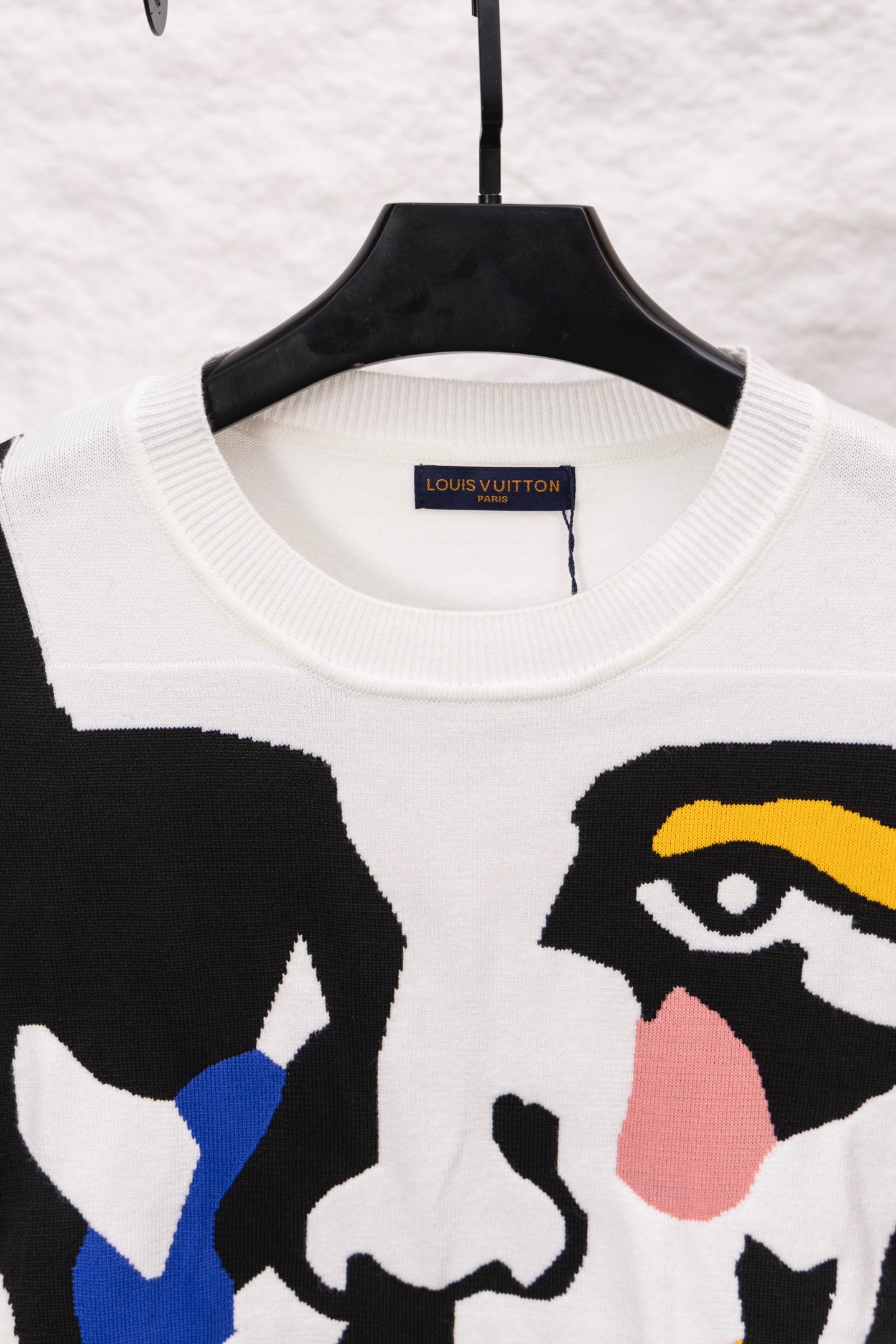 White crewneck sweater with neckline tag and large black graphic face