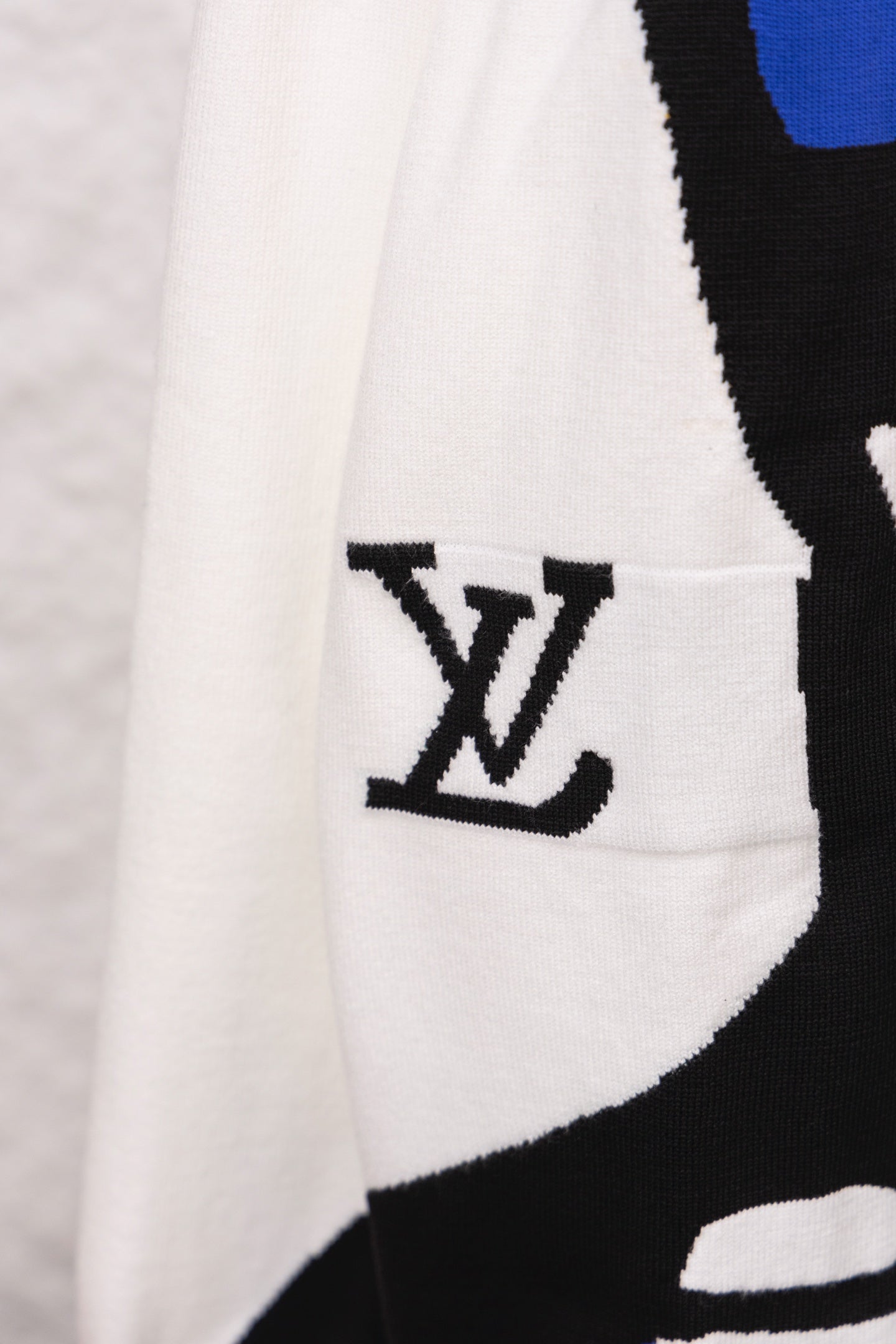White sweater sleeve pocket area with black LV logo graphic