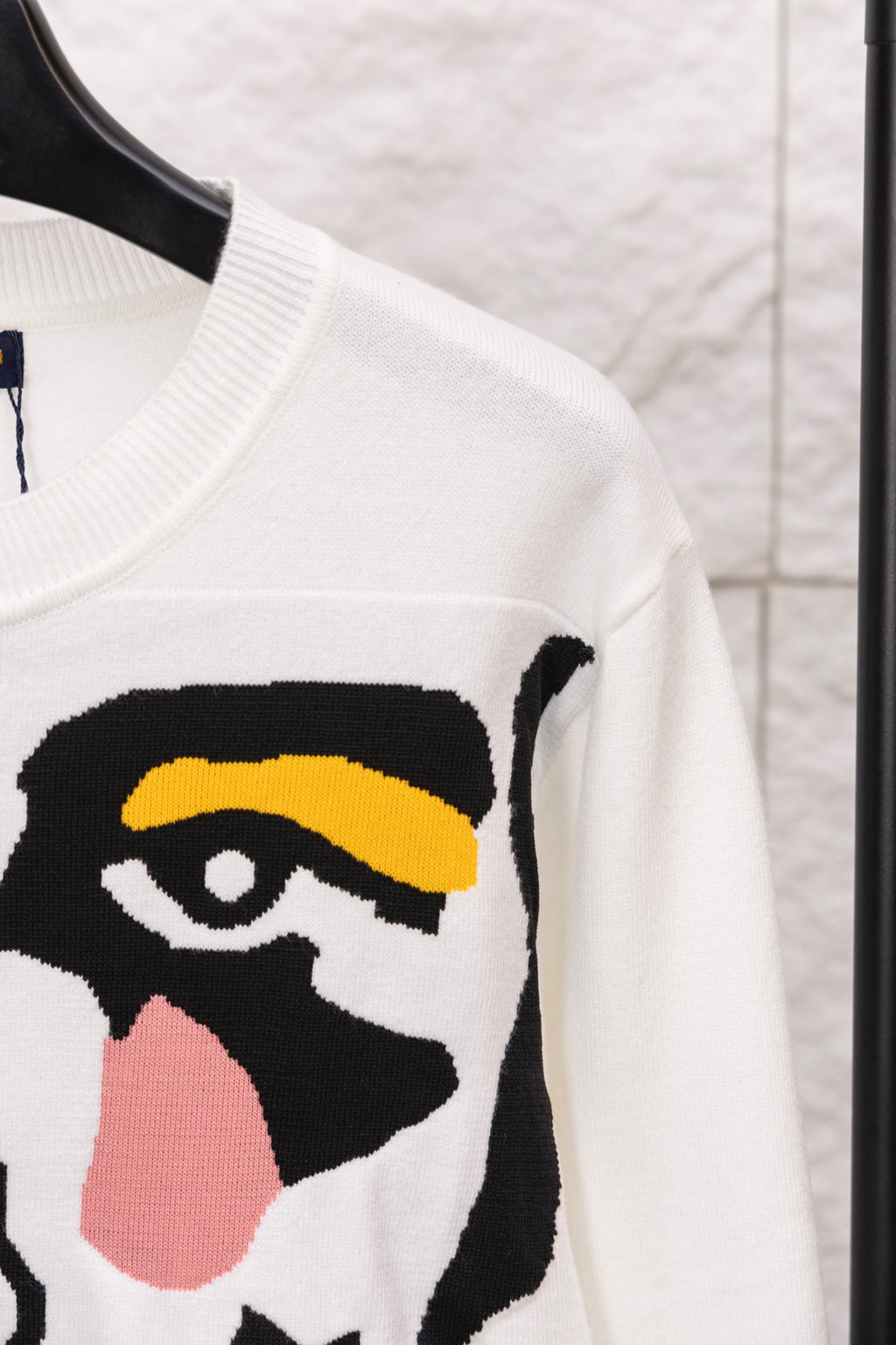 White sweater sleeve with black-and-yellow face graphic panel