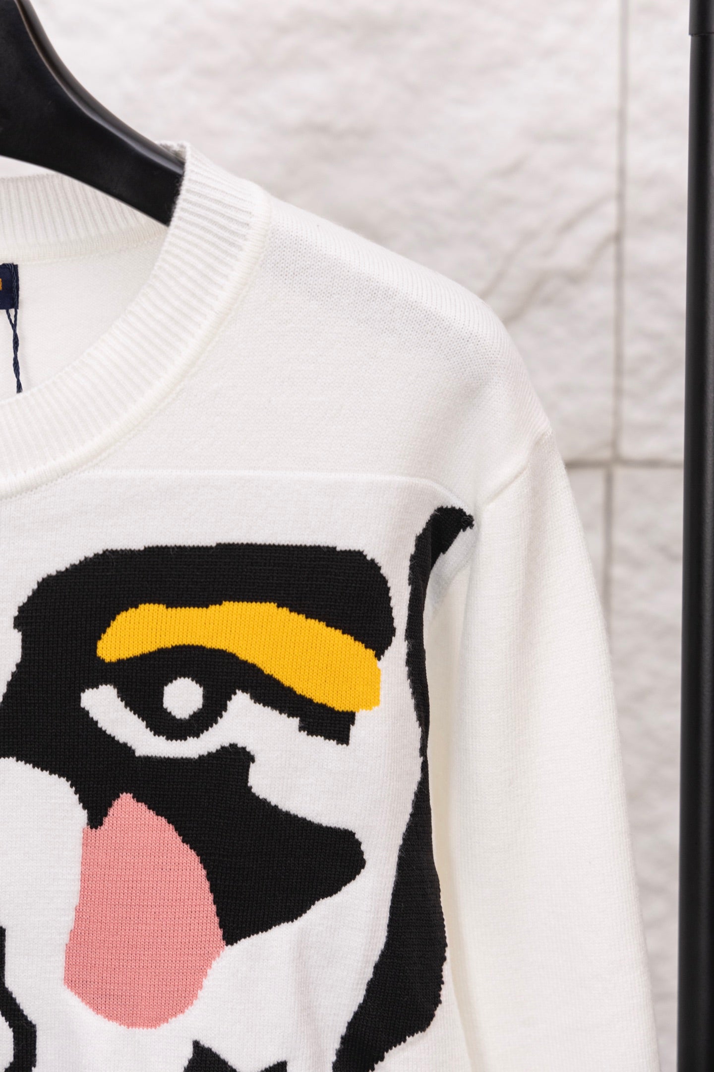 White sweater sleeve with black-and-yellow face graphic panel