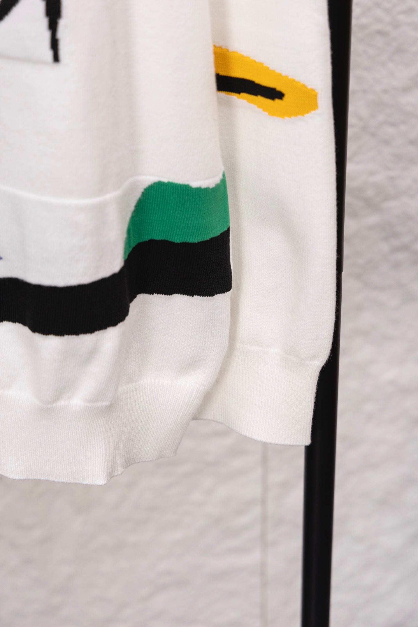 White sweater hem with multicolor striped panel on side