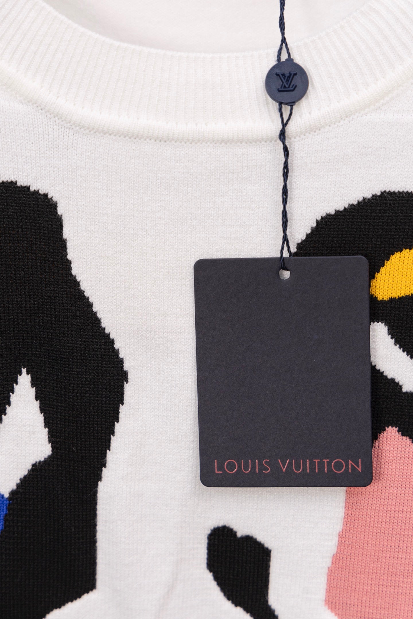 White sweater neckline with hanging brand tag and multicolor face graphic
