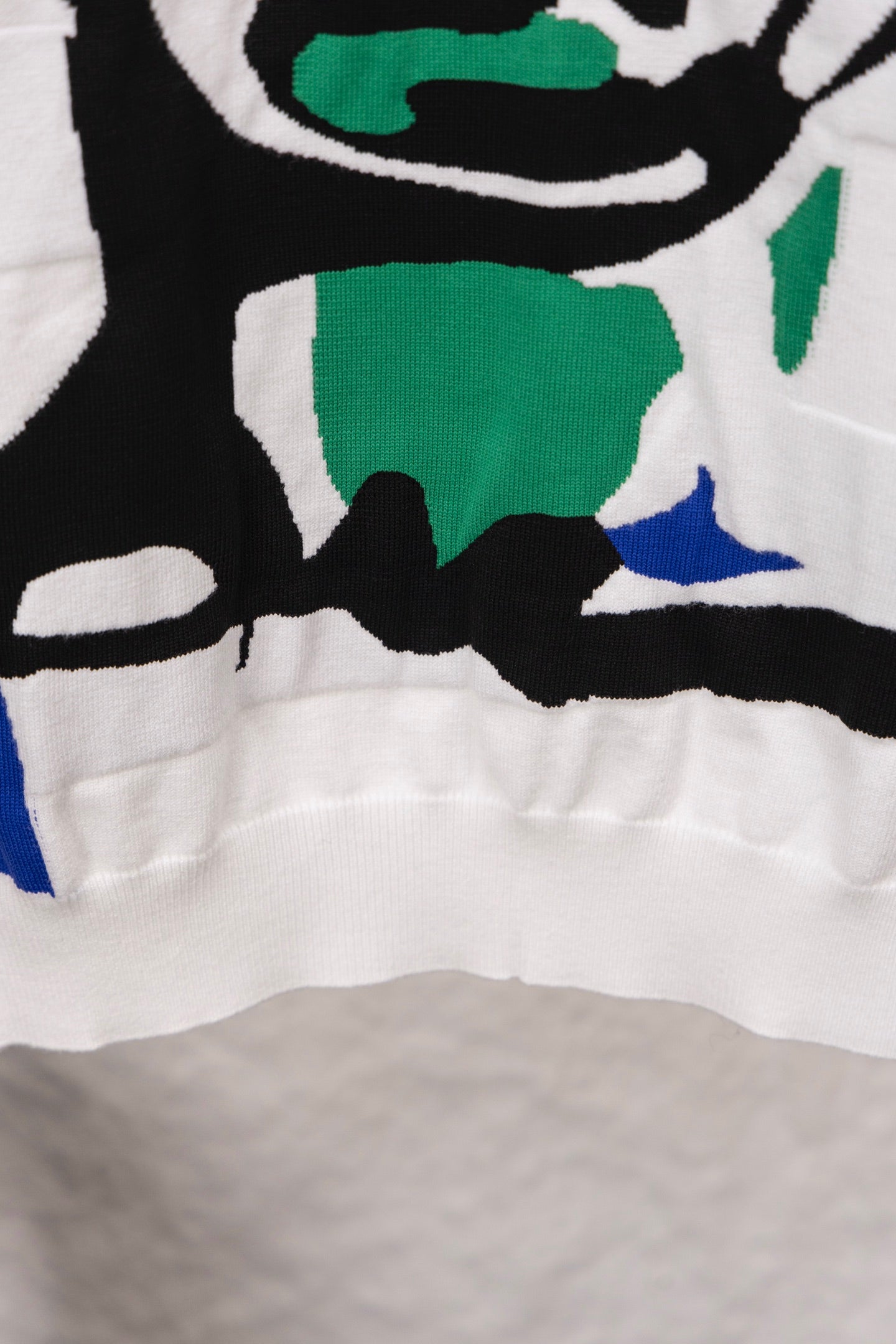 White sweater lower front with colorful graphic shapes near hem