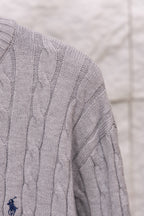 Light gray cable-knit sweater sleeve with small embroidered polo logo