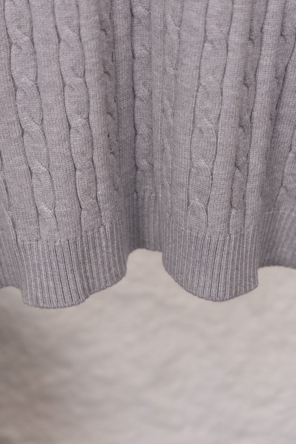 Light gray cable-knit sweater hem with ribbed split cuff detail