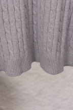 Light gray cable-knit sweater hem with ribbed split cuff detail