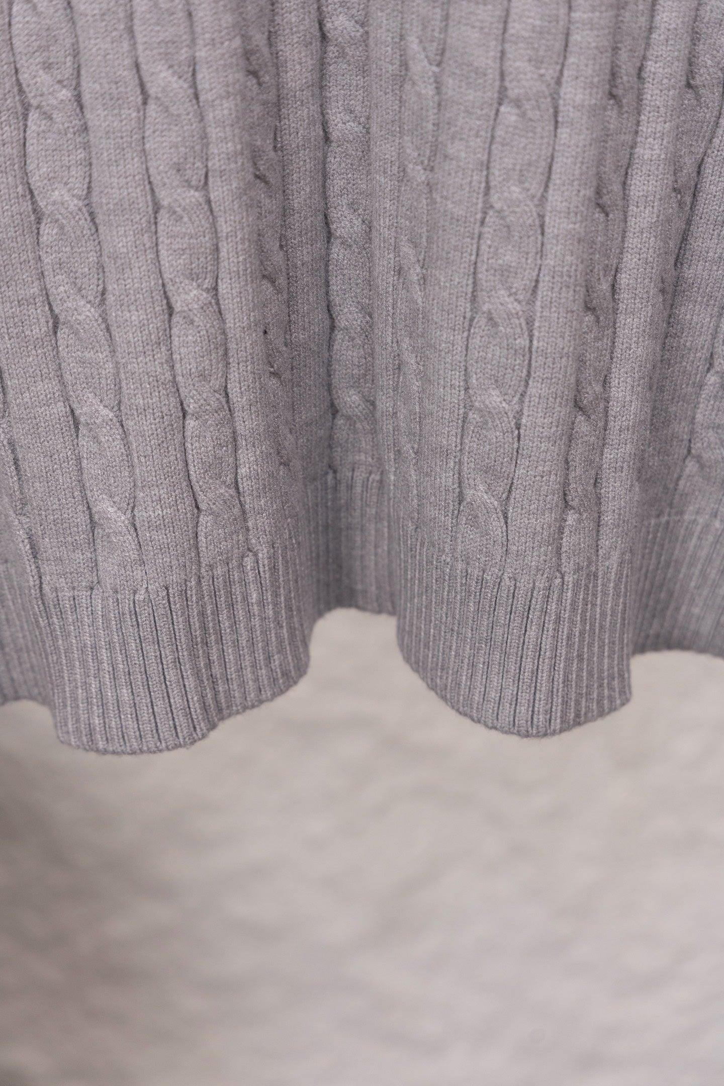 Light gray cable-knit sweater hem with ribbed split cuff detail