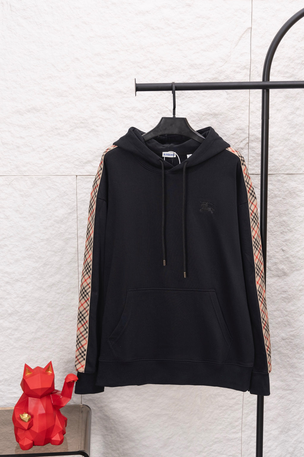 Black long-sleeve hoodie with hood, drawstrings, and check-pattern sleeve stripes