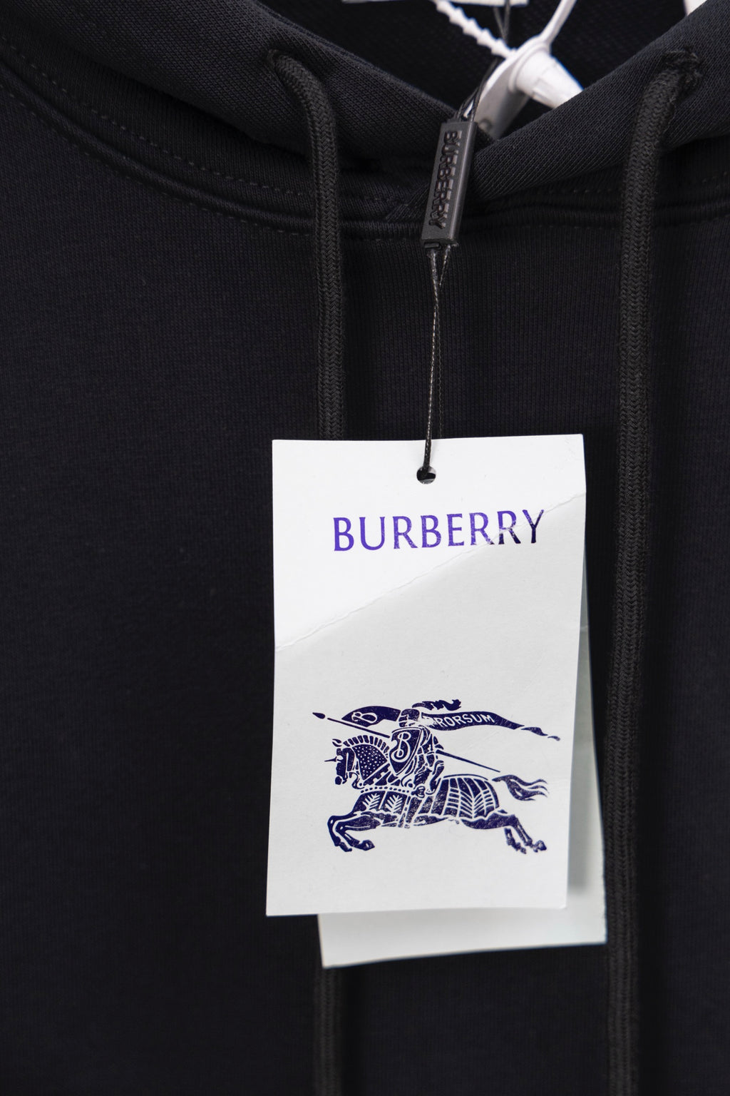 Black hoodie close-up with Burberry logo tag at the hood drawstring area