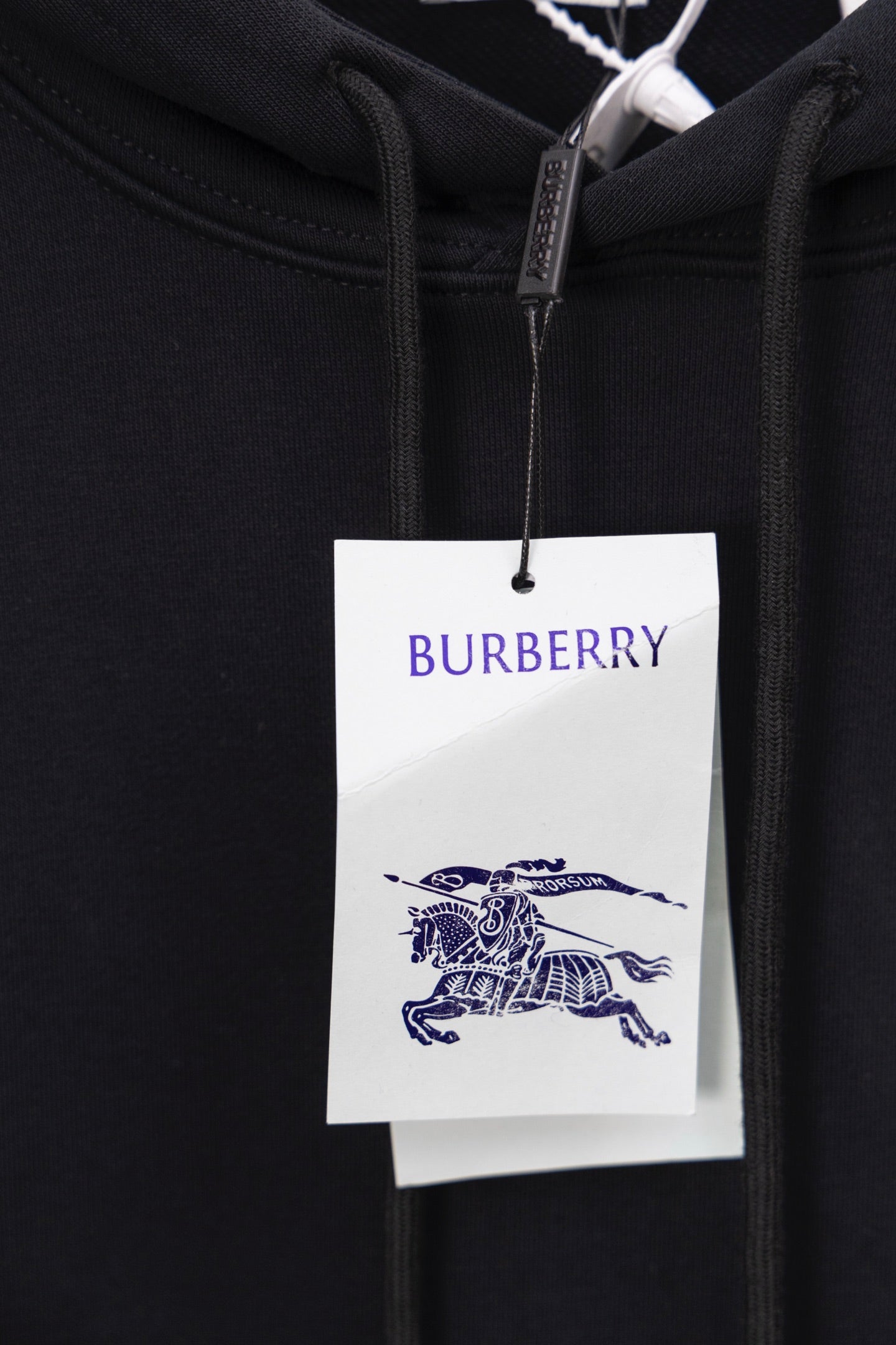 Black hoodie close-up with Burberry logo tag at the hood drawstring area