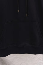 Black hoodie front pocket detail with curved opening and thick edge stitching