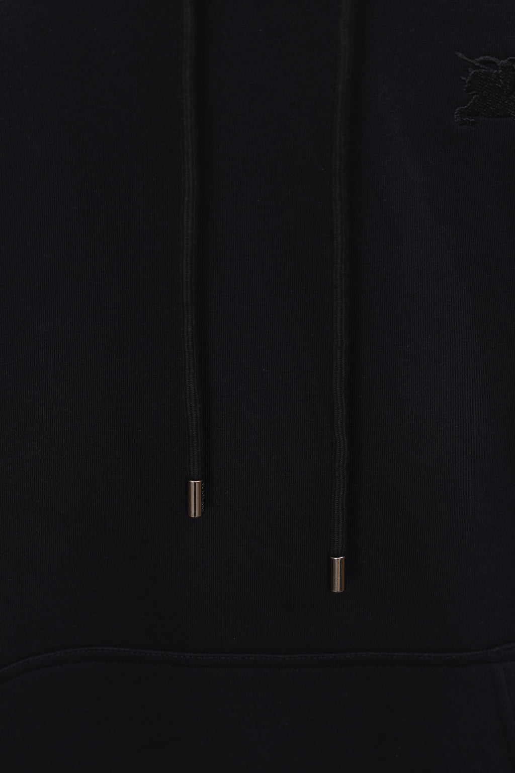 Black hoodie hood drawstrings close-up with metal tips and subtle logo