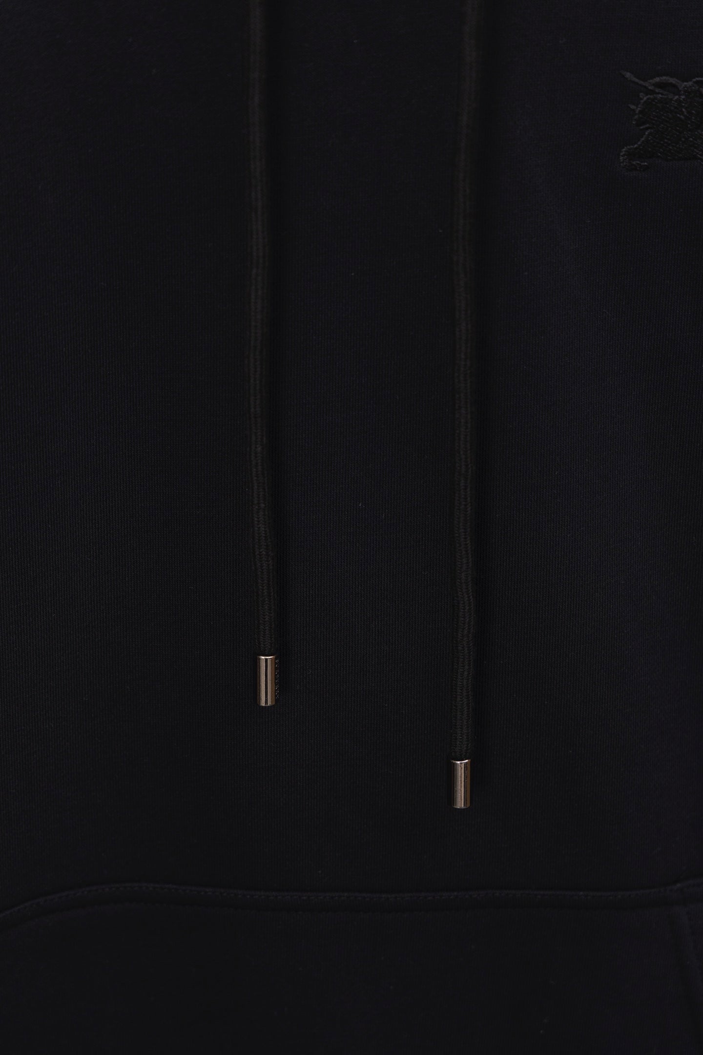 Black hoodie hood drawstrings close-up with metal tips and subtle logo