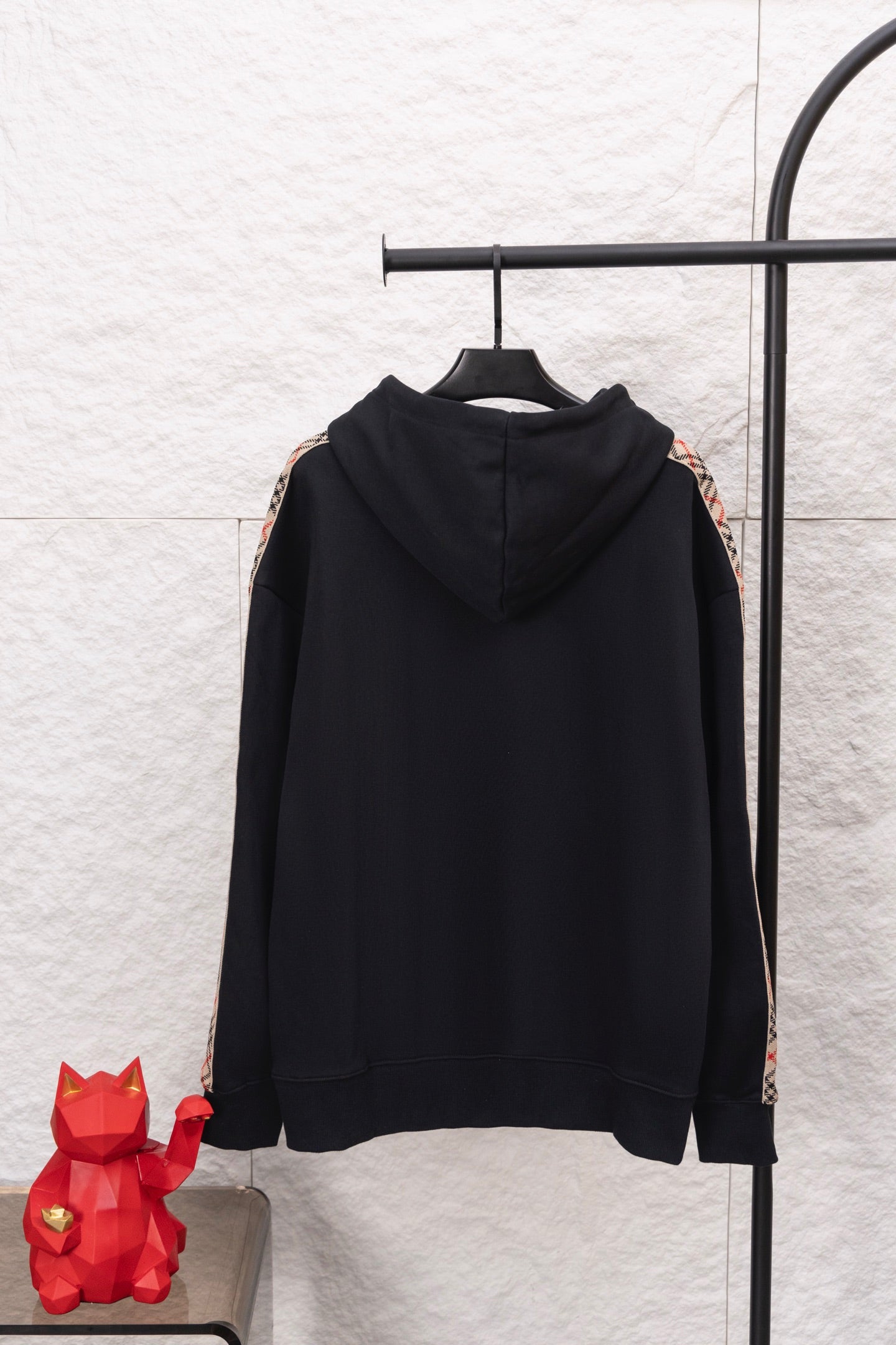 Black hoodie back view with hood and drawstrings, plus check stripe sleeve panels