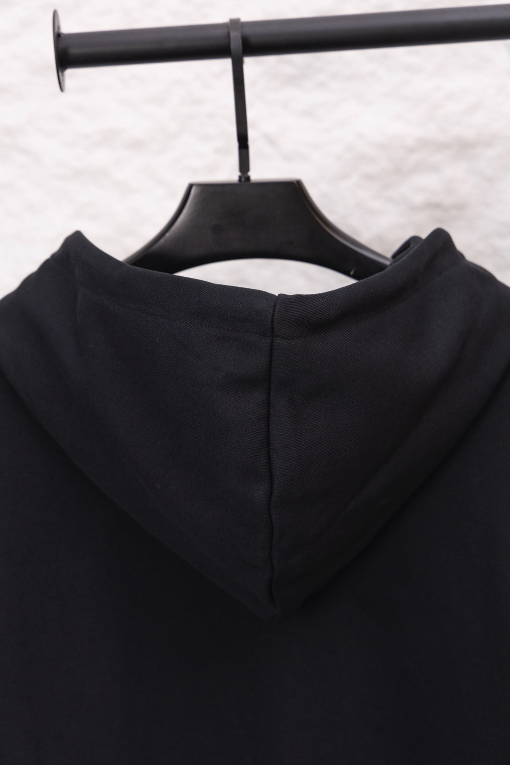 Black hoodie hood back with inner seam and drawstring ends on hanger