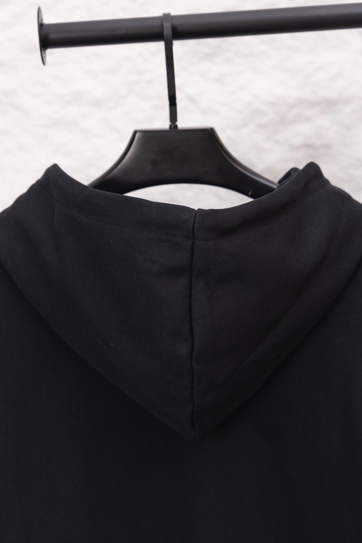 Black hoodie hood back with inner seam and drawstring ends on hanger