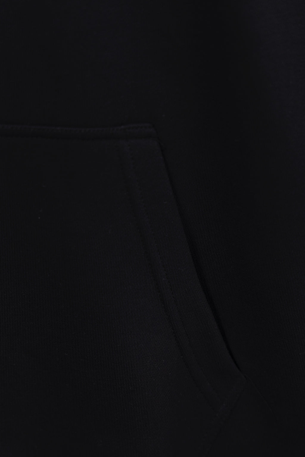 Black hoodie fabric close-up with waist seam and stitched panel detail
