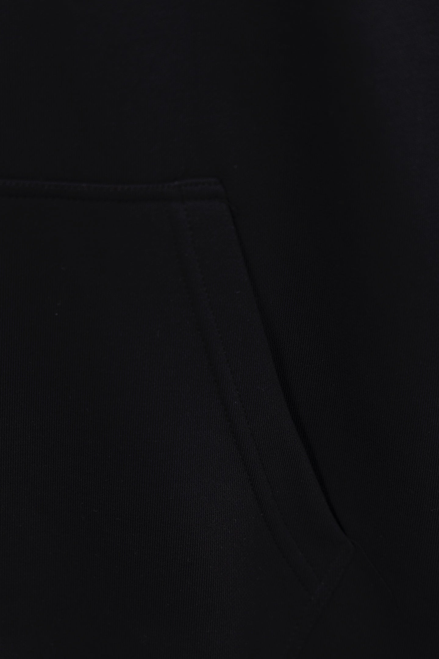 Black hoodie fabric close-up with waist seam and stitched panel detail