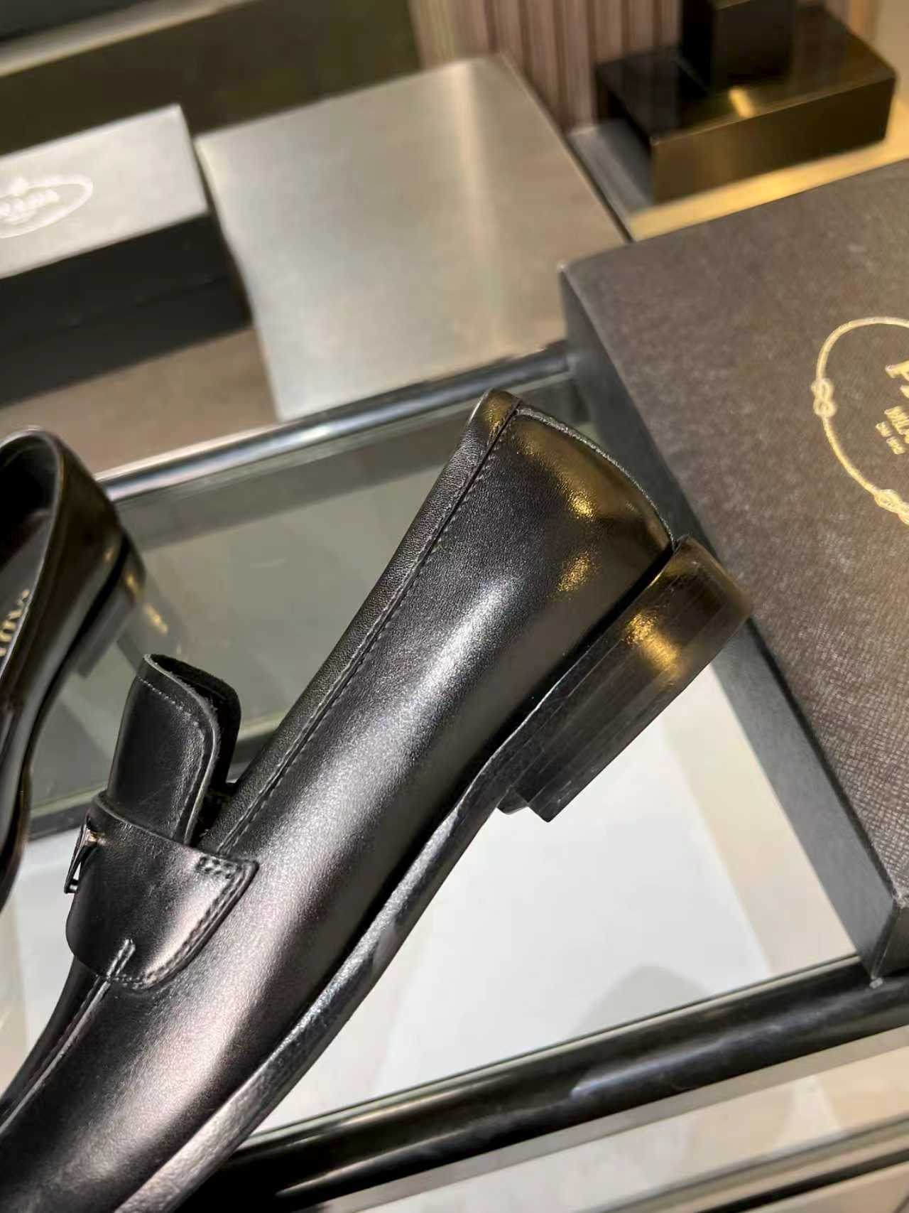 Prada black leather loafer close side view with block heel and rounded toe