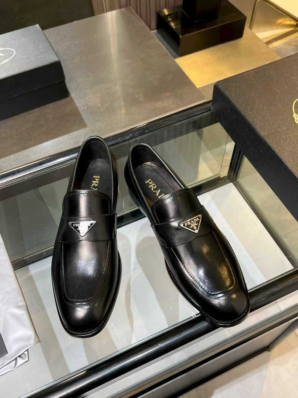 Prada black leather loafers, angled front view with front metal crest