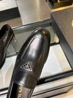 Prada black leather loafer close-up of side seam and front metal logo