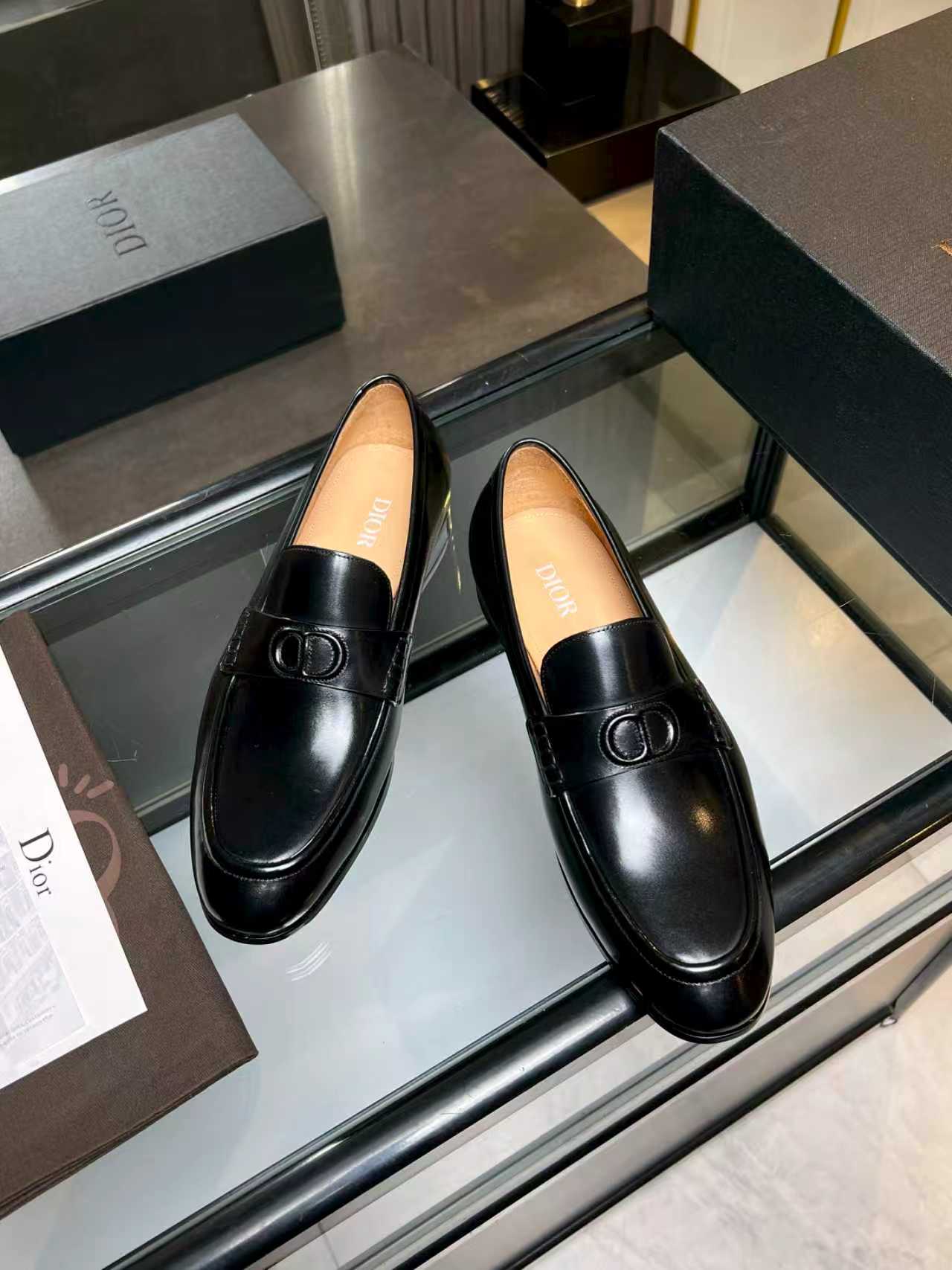 Black leather loafers with Dior monogram buckle, angled view