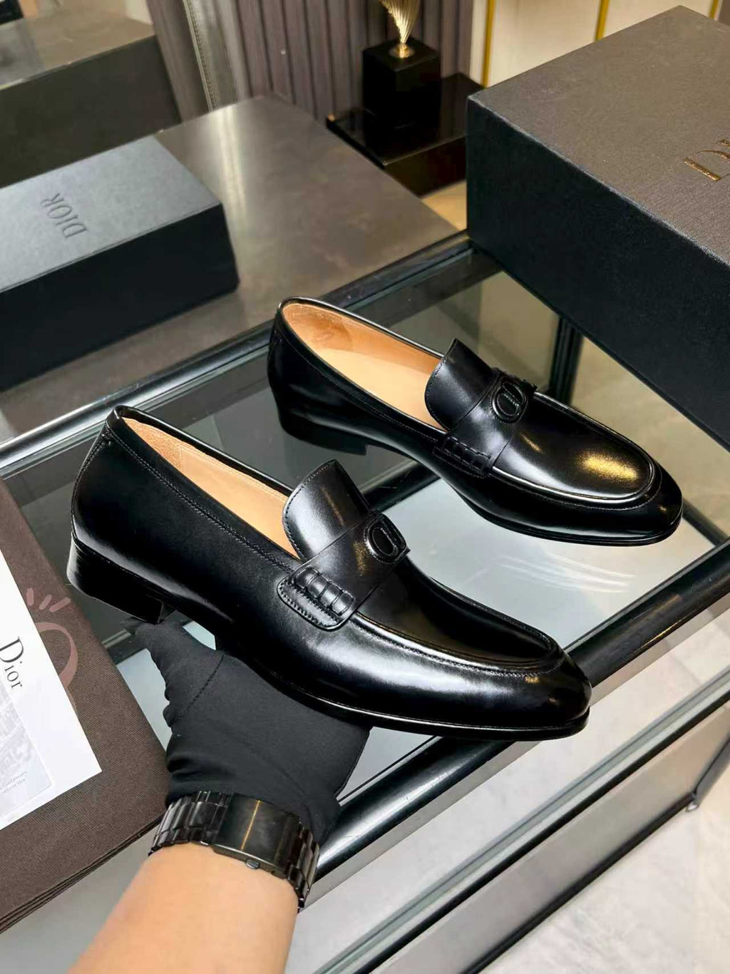 Black leather loafers with Dior emblem buckle, shown from side and top