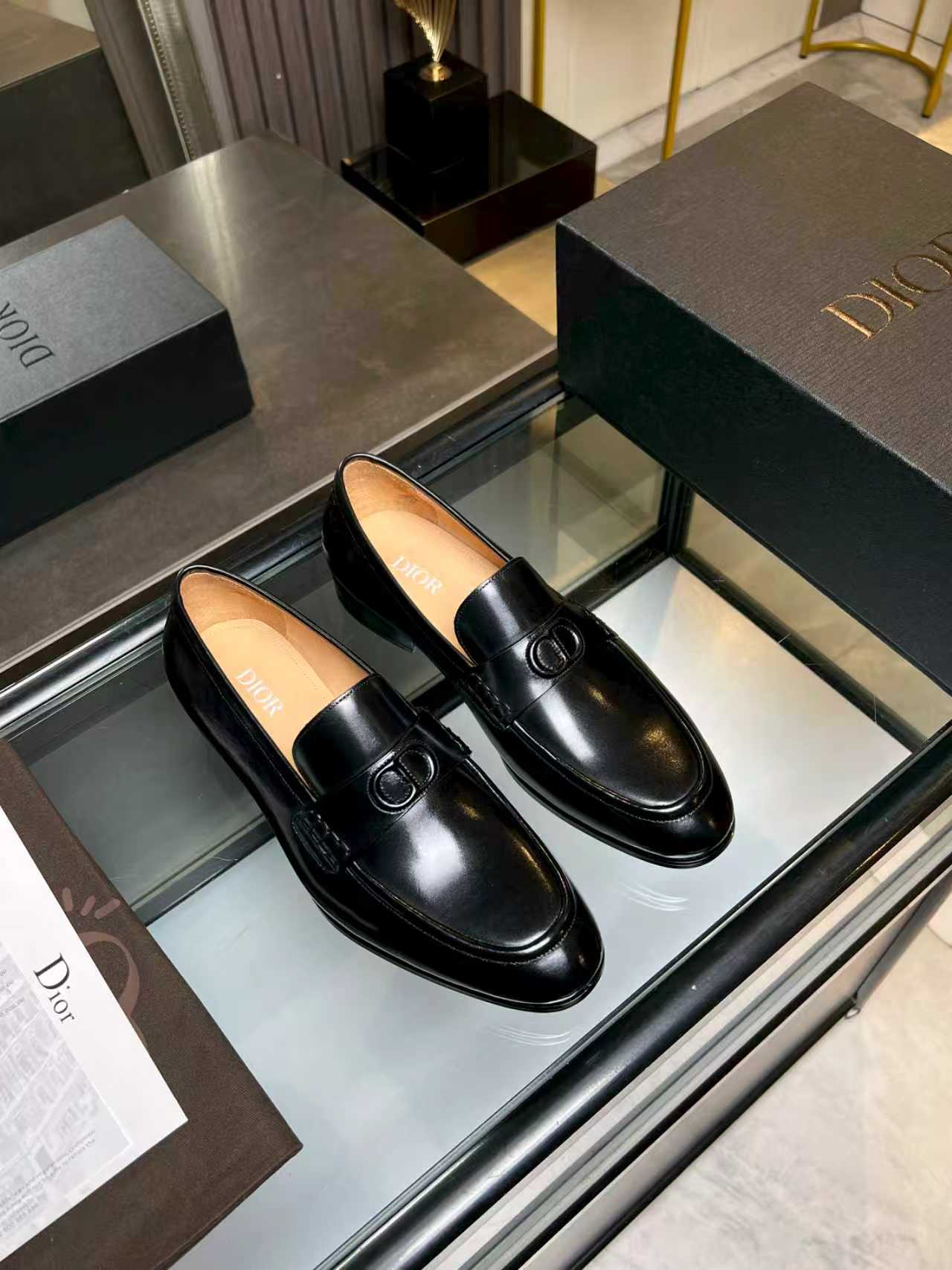 Pair of black leather loafers with round Dior emblem buckle on front