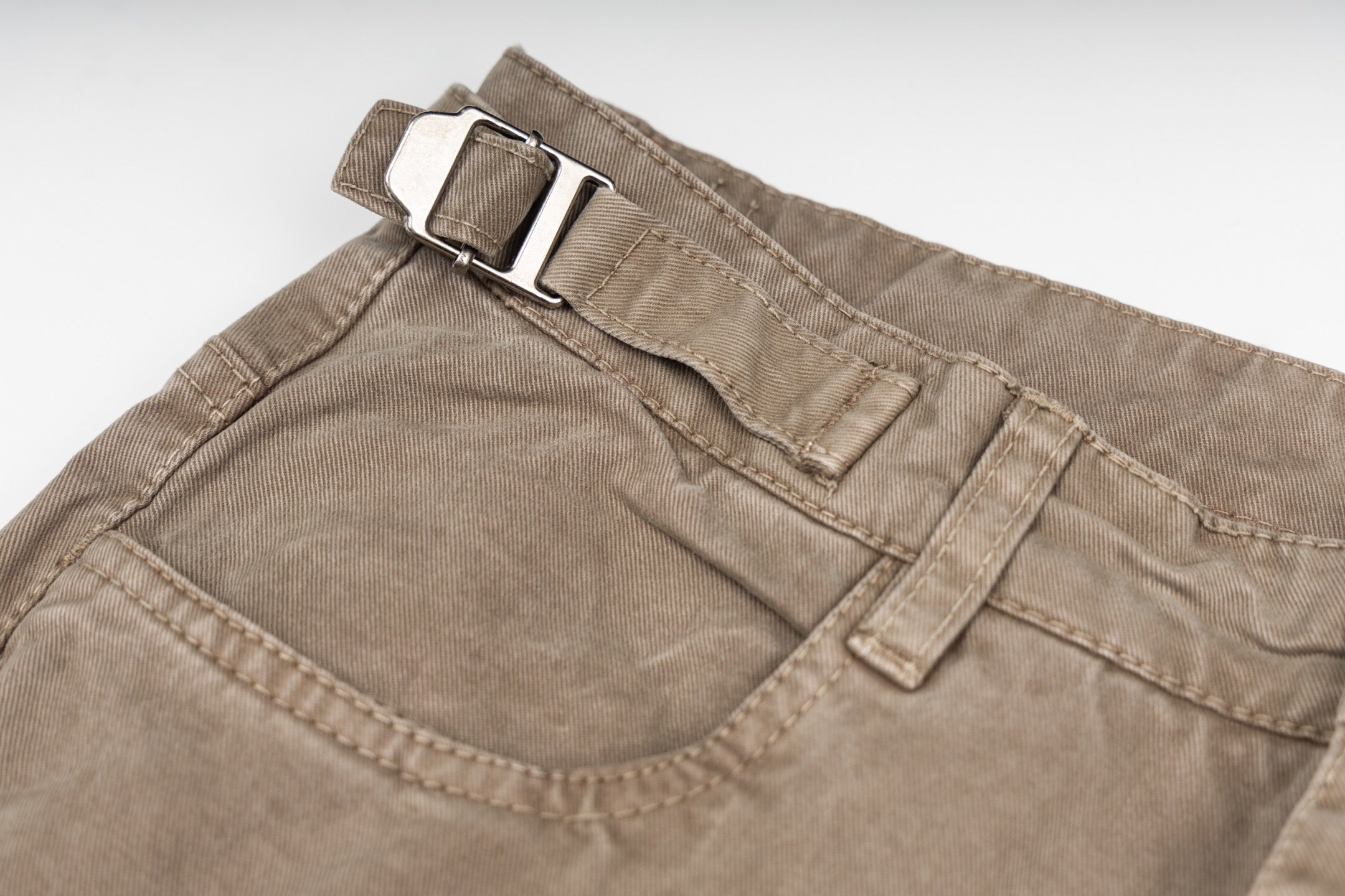 Tan cargo pants waistband detail with belt loops and buttoned closure