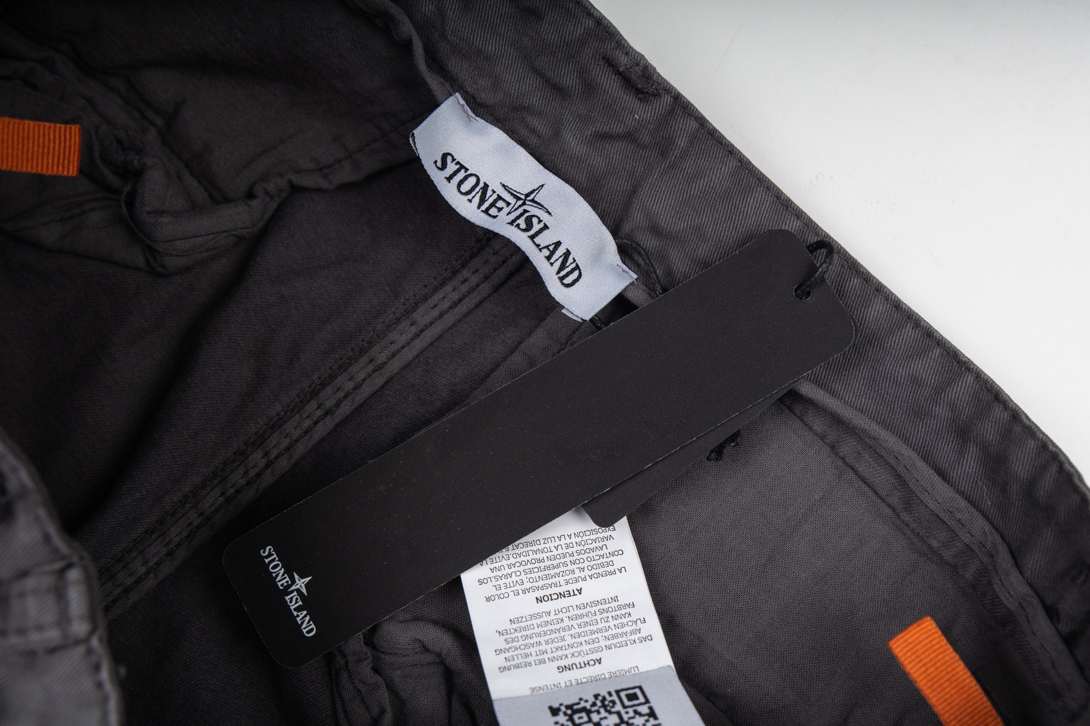 Stone Island cargo pants interior tags and orange accent on dark gray lining