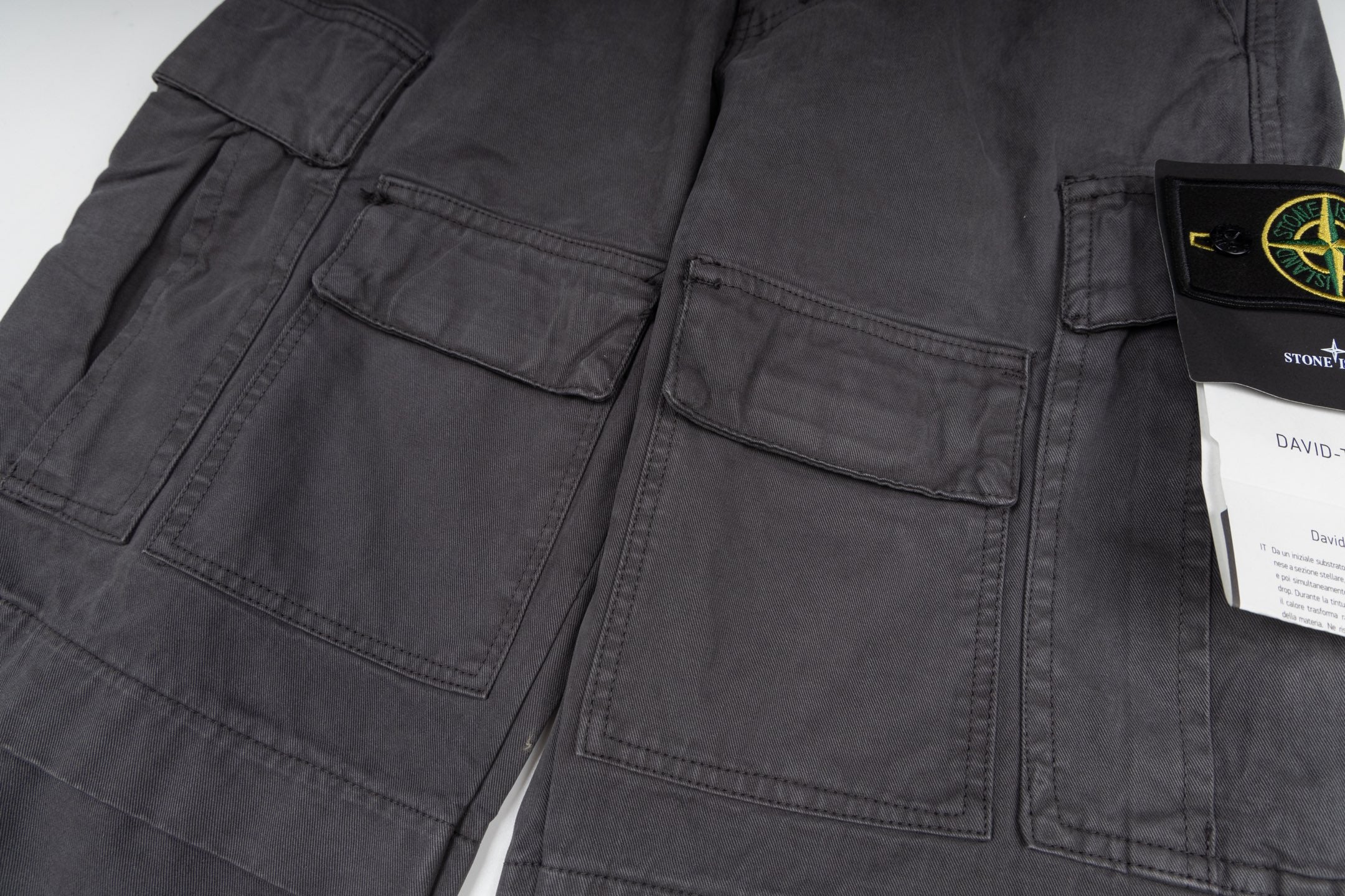 Stone Island cargo pants detail view, dark gray stitched pockets and seams