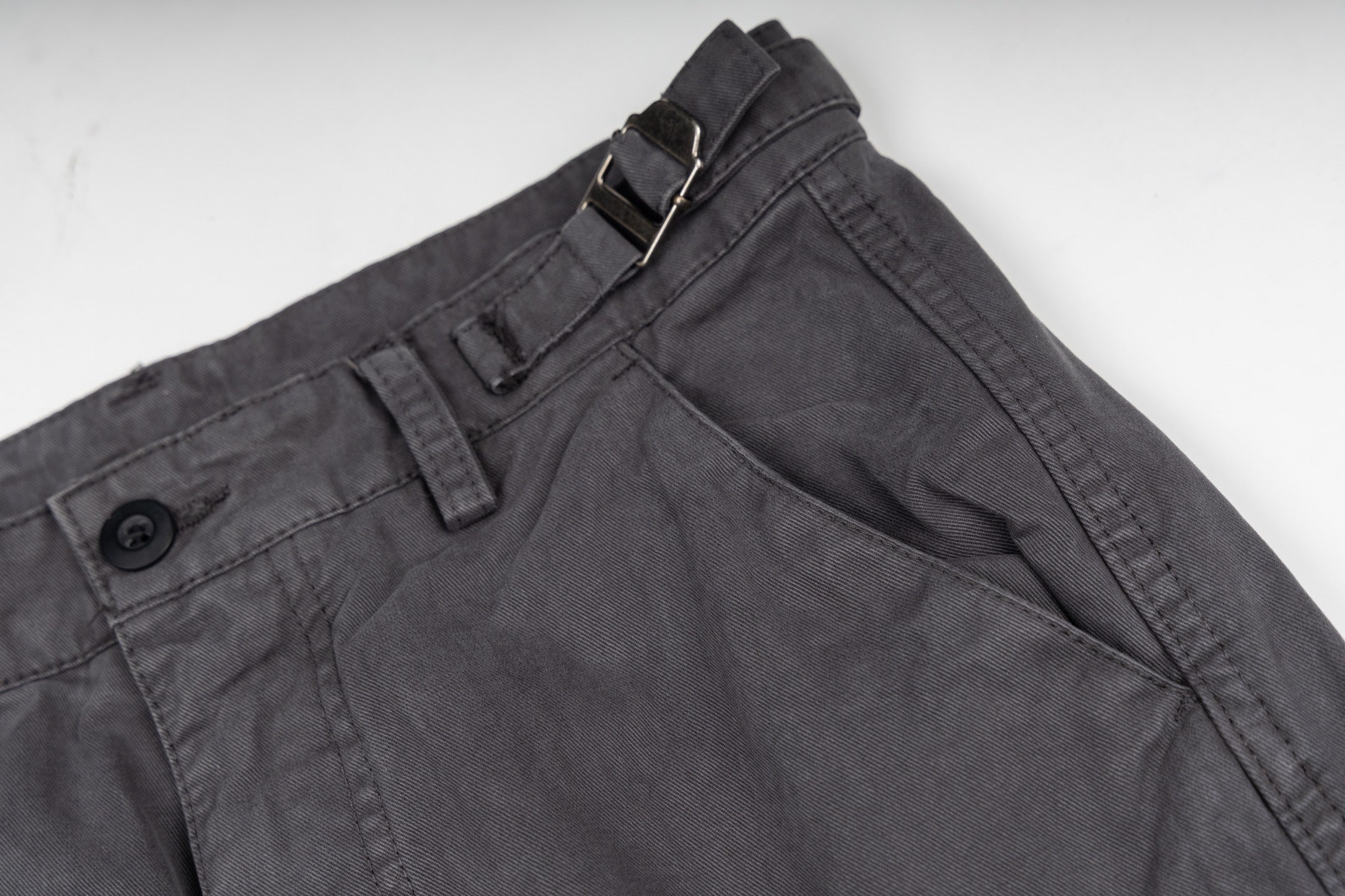 Stone Island cargo pants front view, dark gray with button and zipper placket
