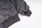 Dark gray bomber jacket sleeves with ribbed cuffs and snap button chest pocket